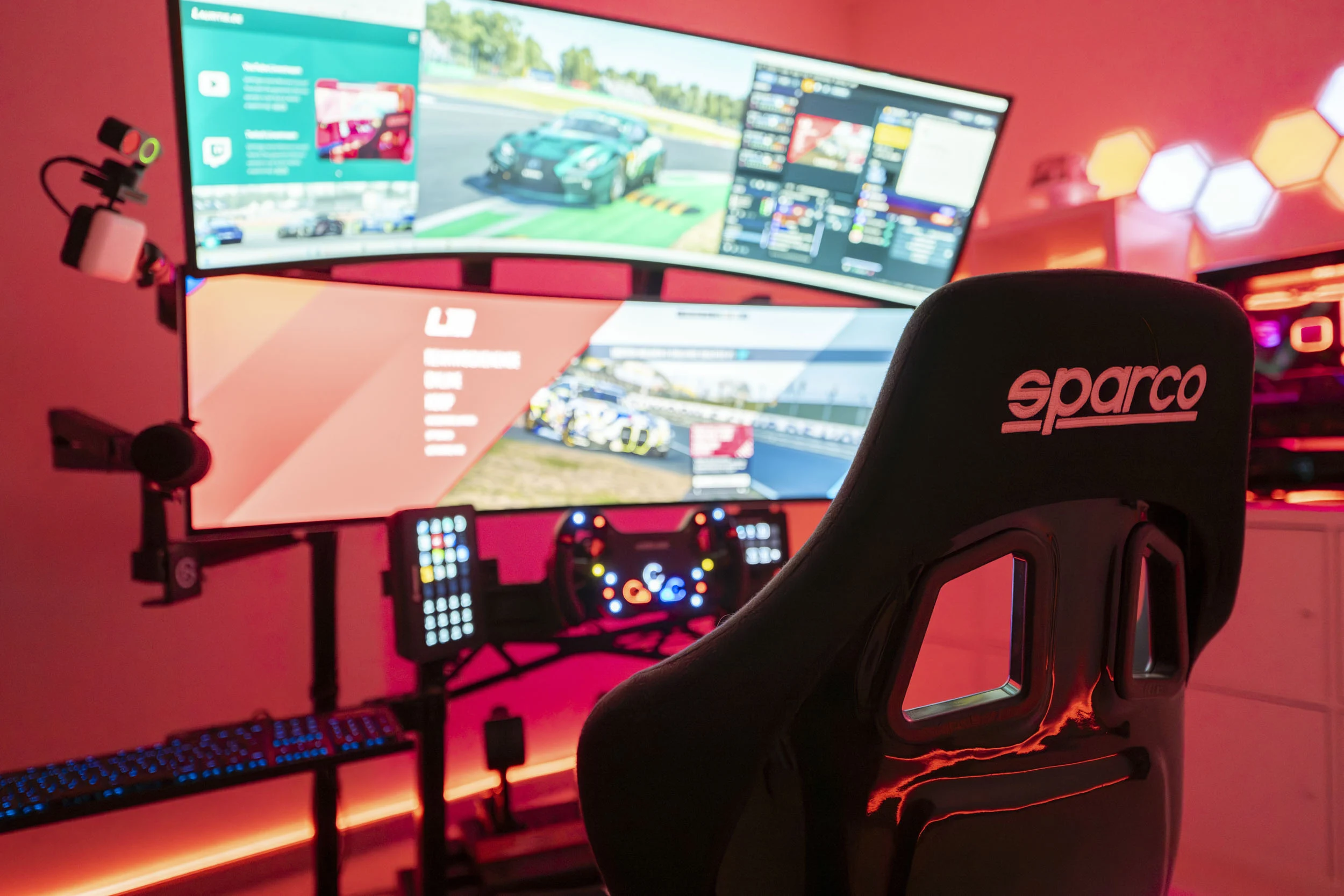 Curved Ultrawide Monitor Showing a Racing Game with a Sparco Gaming Chair and Pink Ambient Lighting in a Dedicated Setup Room