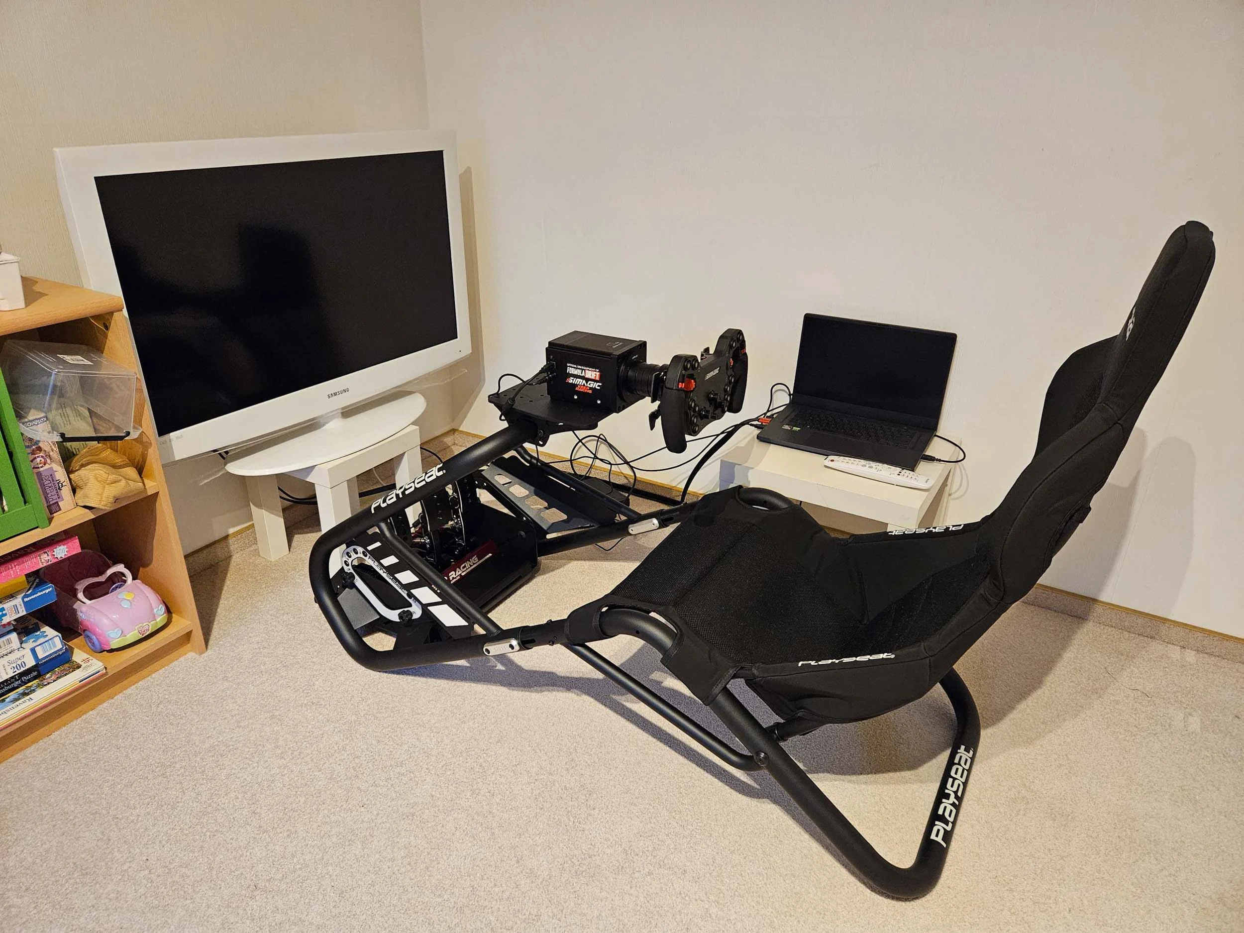 simracingpeterlauritisgt3simulation001 | Lauritisde Racing Simulator Setup in a Room Playseat Frame with Steering Wheel and Pedals Large Wall mounted Monitor and a Laptop on a Small Table Nearby