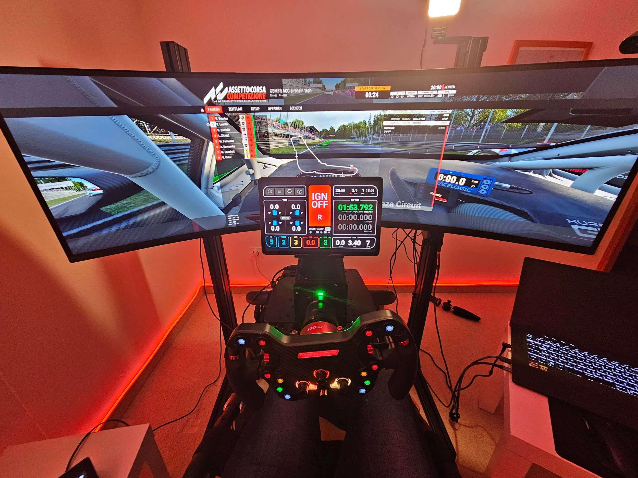 simracingpeterlauritisgt3simulation006 | Lauritisde Racing Simulator Cockpit with a Multi monitor Wraparound Display Showing Assetto Corsa Competizione Steering Wheel with Colored Buttons and a Laptop Nearby on the Right