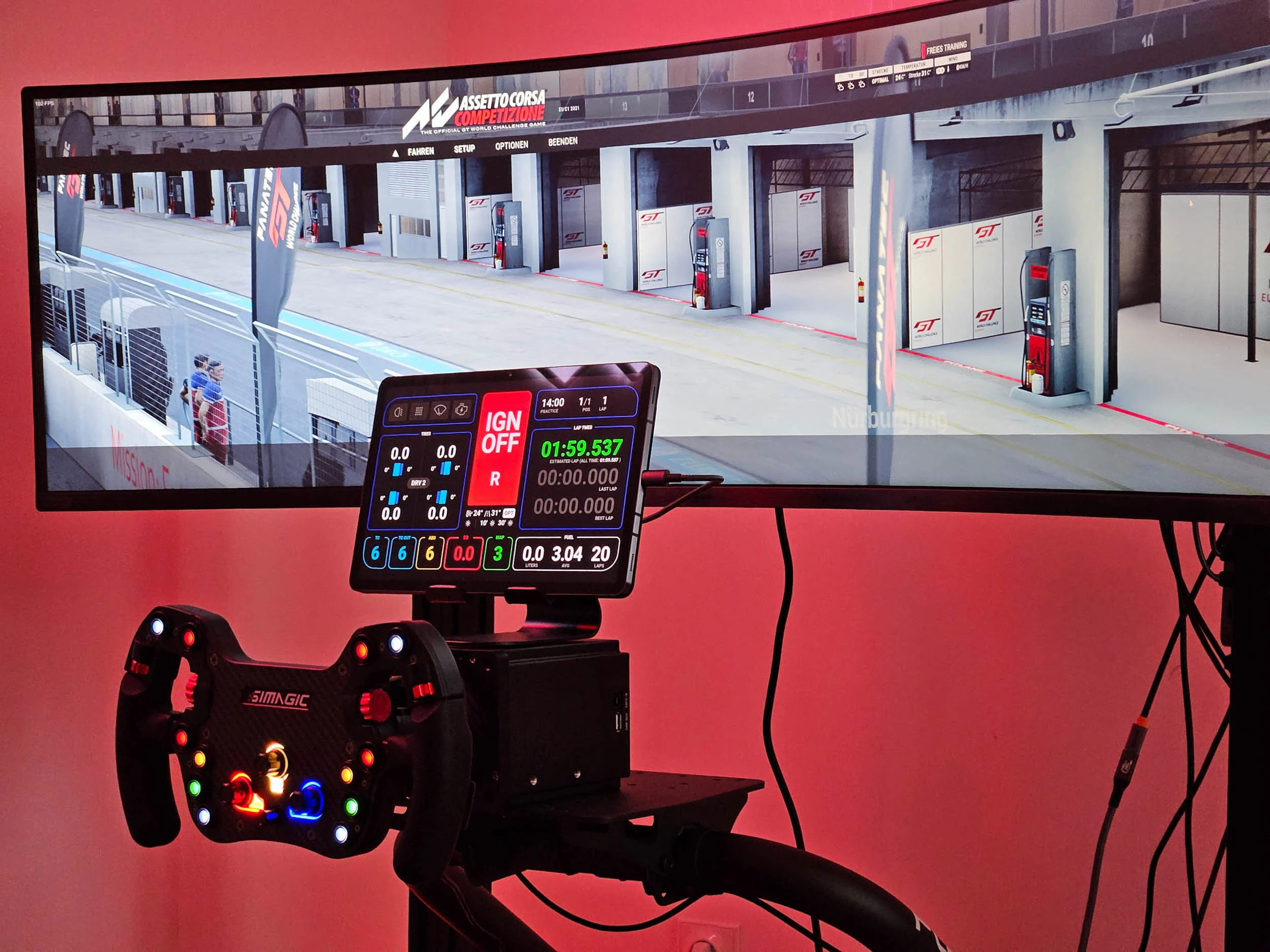 simracingpeterlauritisgt3simulation008 | Lauritisde Racing Simulator Setup with a Colorful Wheel Controller in Front of a Large Monitor Showing a Pit lane Scene from a Racing Game