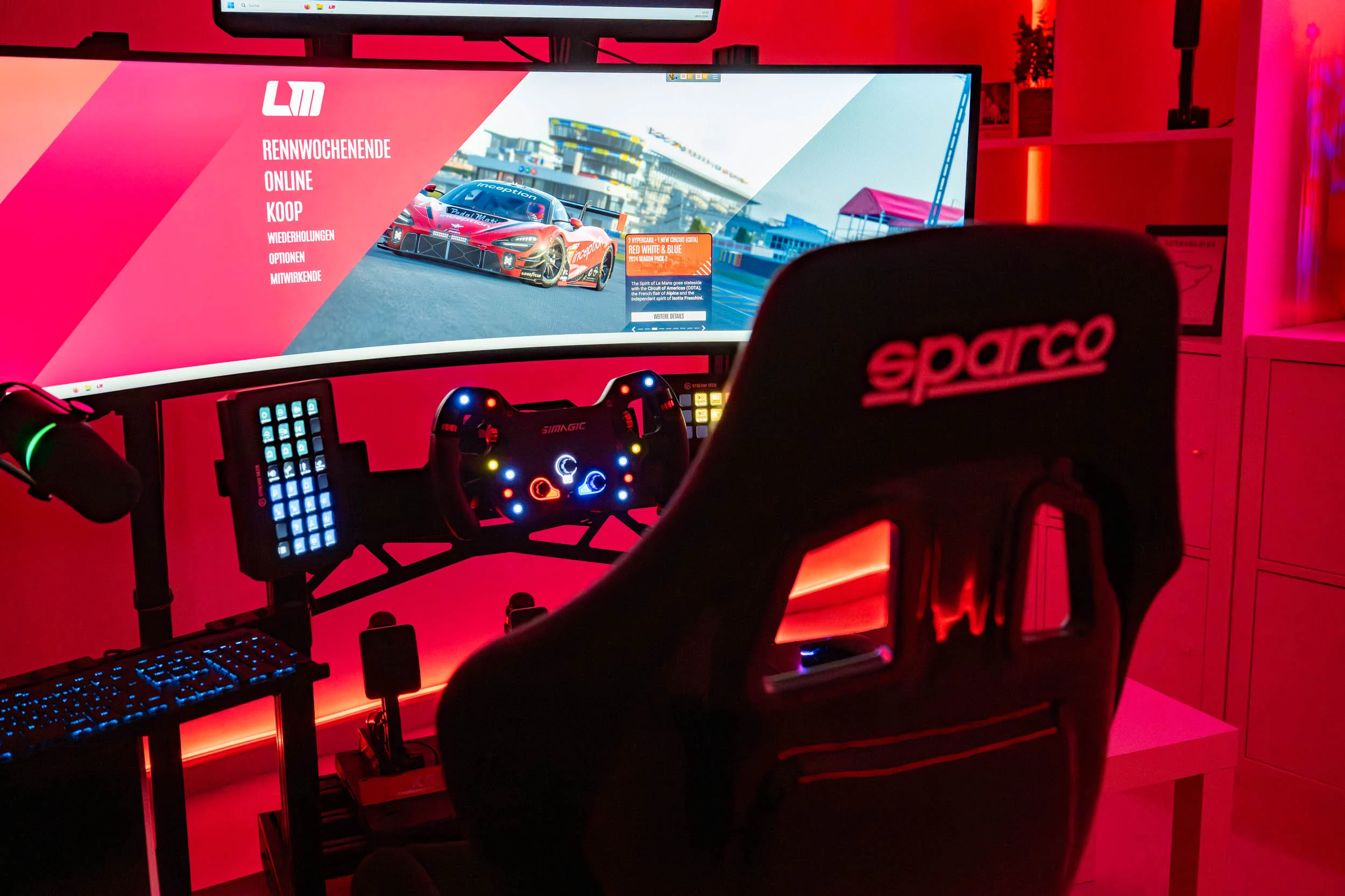 wwwpeterlauritisde | Lauritisde Wide Monitor Shows a Car Race in a Red lit Sim Racing Setup with a Racing Wheel Pedals Keyboard and a Sparco Chair Nearby