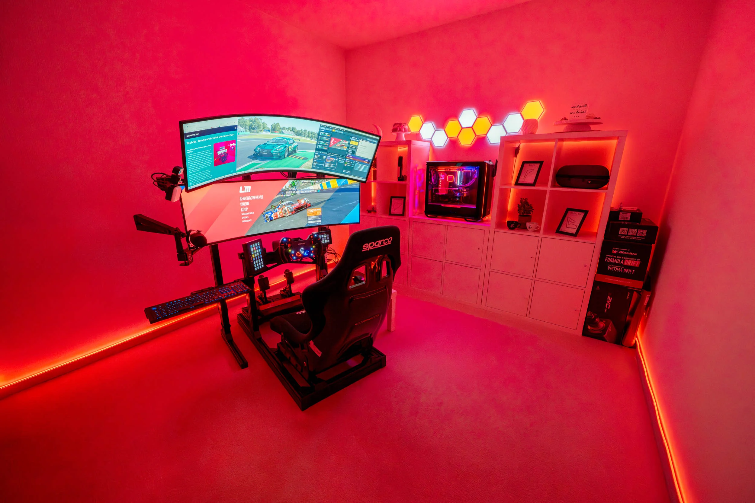 wwwpeterlauritisde | Lauritisde Red lit Gaming Room with a Curved Multi screen Racing Setup Racing Chair Pedals and Shelving with a Pc Components Visible Beneath Glow Strips